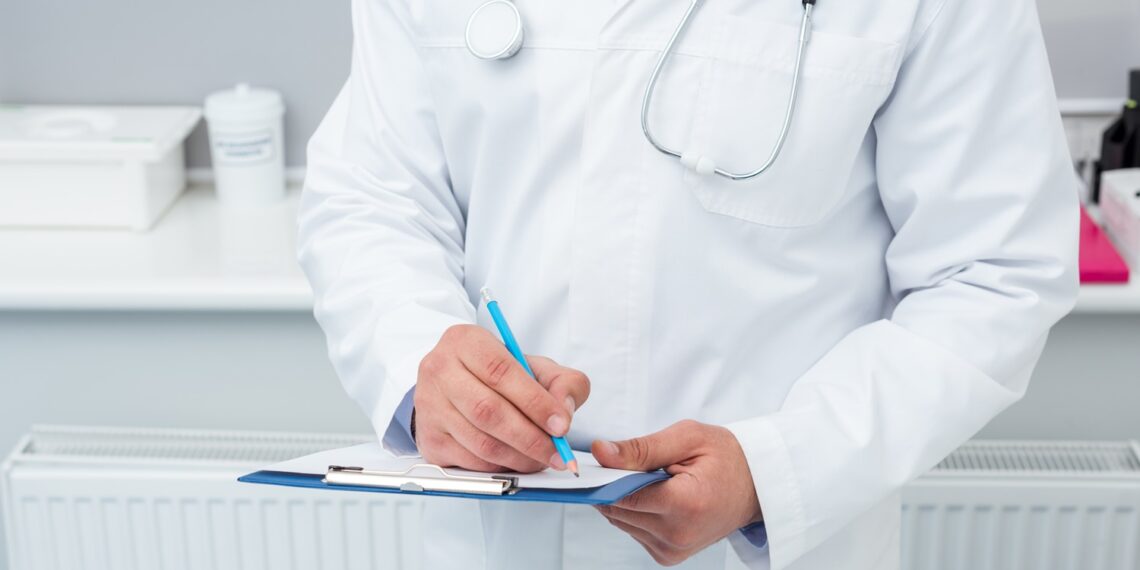 cropped shot of doctor writing in clipboard