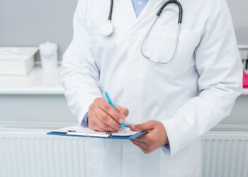 cropped shot of doctor writing in clipboard